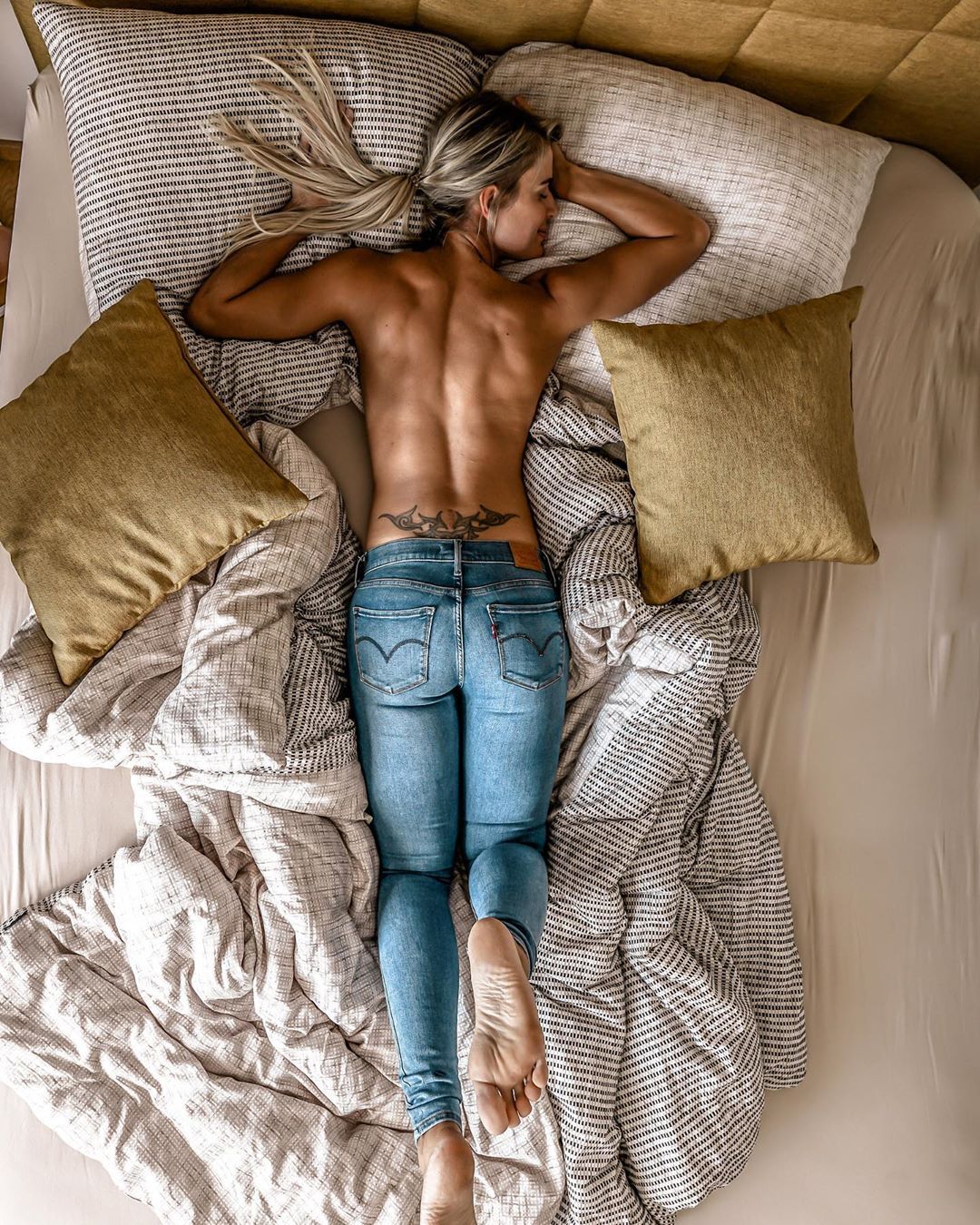 1080x1350, 378 Kb / блондинка, джинсы, тату, кровать, подушки, спина, рельеф